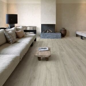 Quick-Step Alpha Bloom Botanic Grey vinyl flooring in living room with fireplace and neutral decor