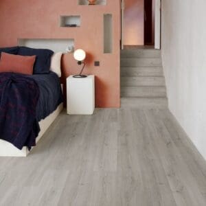 Quick-Step Alpha Bloom Botanic Grey vinyl flooring in bedroom with coral accent wall