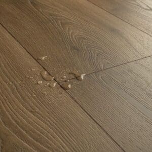 Close-up detail of Quick-Step Warm Brown Oak laminate flooring showing impression bevel edges