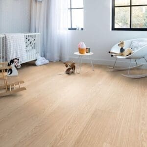 Quick-Step Alpha Bloom Pure Oak Blush vinyl flooring installed in a modern nursery with white furniture and soft decor
