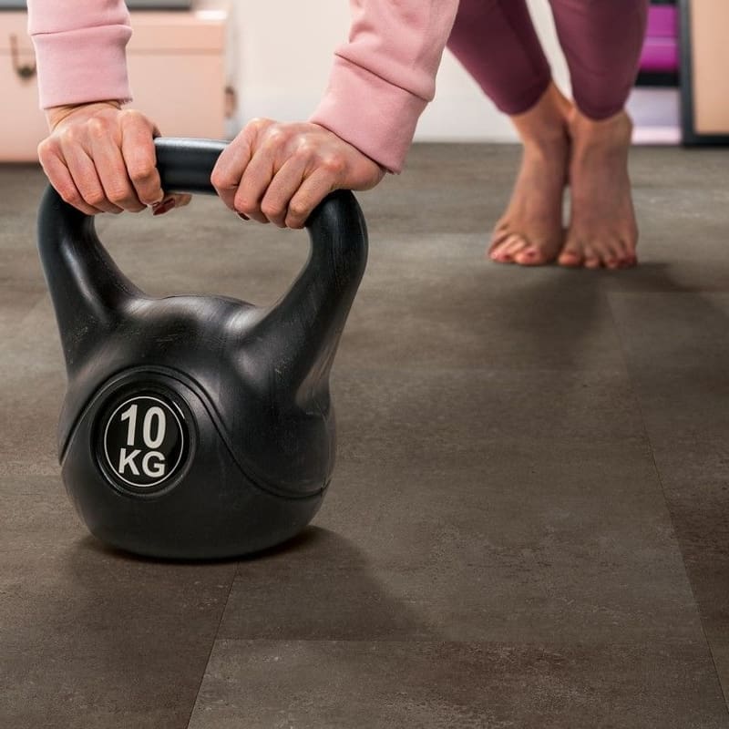 Quick-Step Alpha Oro Oxidized Rock vinyl flooring in a home gym setting with exercise equipment