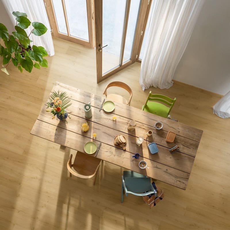 Family breakfast scene with dog on Quick-Step Alpha Bloom Brushed Oak Honey vinyl flooring