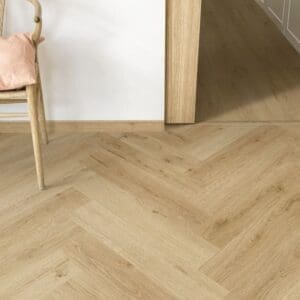 Close-up of Quick-Step Alpha Ciro Botanic Beige Herringbone flooring with chair leg