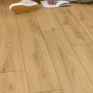 Quick-Step Classic Sandy Oak Laminate flooring in a living room with person sitting playing guitar
