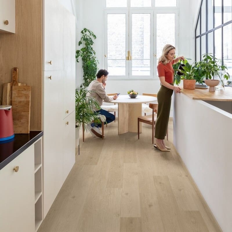Modern kitchen with Quick-Step Alpha Blos Coast Oak Sand flooring installed showing bright, airy space