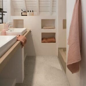 Oyster Concrete flooring in a minimalist bathroom with white walls and wooden accents