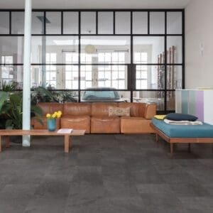 Quick-Step Alpha Oro Black Slate vinyl flooring installed in a modern living space with leather furniture