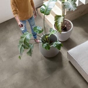Person watering plants on Quick-Step Cloudy Concrete flooring showing its waterproof properties