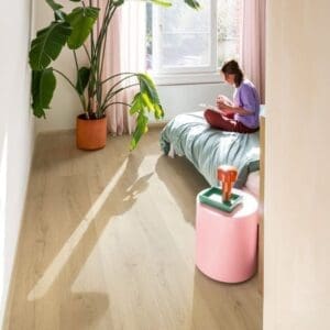 Bedroom with Quick-Step Brushed Oak Beige flooring, pink curtains and houseplant