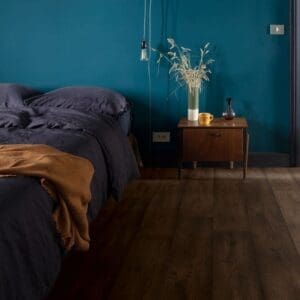 Bedroom with Quick-Step Waxed Oak Brown laminate flooring featuring teal walls and modern decor