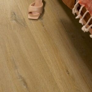 Close-up of Cotton Oak Deep Natural flooring with beige shoes and orange bedding