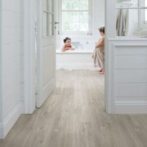 Quick-Step Canyon Oak Grey vinyl flooring installed in a bright white bathroom