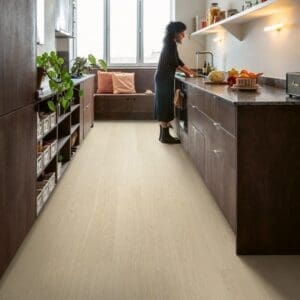 Quick-Step Alpha Bloom Pure Oak Polar vinyl flooring installed in a modern kitchen with dark cabinetry