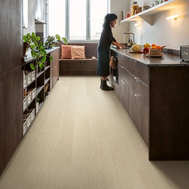 Quick-Step Alpha Bloom Pure Oak Polar vinyl flooring installed in a modern kitchen with dark cabinetry