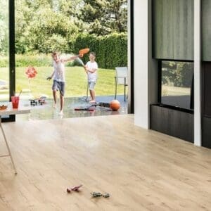 Modern living space with Quick-Step Impressive Classic Oak Beige laminate flooring and outdoor view