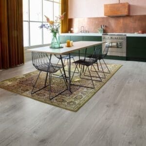 Quick-Step Alpha Bloom Cotton Oak Cold Grey flooring installed in a contemporary kitchen with green cabinetry and dining area