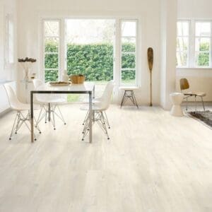 Modern dining room with Quick-Step Charlotte Oak White laminate flooring installed, showcasing bright and airy aesthetic