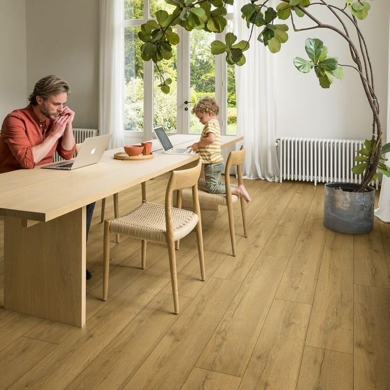 Family dining room with honey oak laminate flooring and large plant