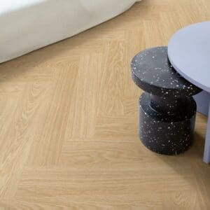 Close-up of person sitting on kitchen stool with Quick-Step Alpha Ciro Pure Oak Blush flooring visible below