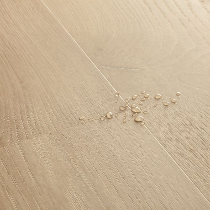 Detail of Quick-Step Alpha Blos Coast Oak Sand showing water droplets demonstrating waterproof properties