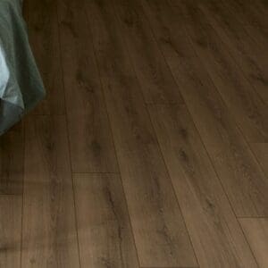 Bedroom with Quick-Step Warm Brown Oak laminate flooring, white side table and mint green bedding