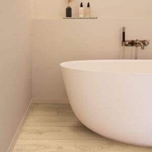 Bathroom installation of Quick-Step Desert Greige Oak laminate flooring with freestanding bathtub showing practical application