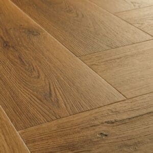 Close-up of Quick-Step Alpha Ciro Botanic Caramel Oak herringbone pattern luxury vinyl flooring showing detailed wood grain texture