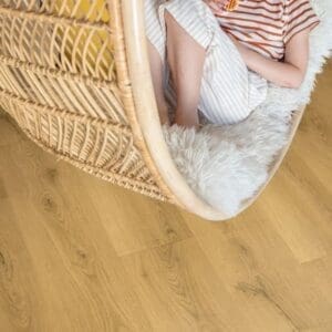 Child sitting in rattan hanging chair on Quick-Step Classic Light Classic Oak Laminate flooring