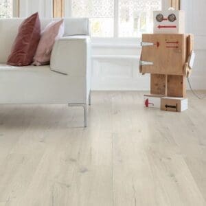 Close-up of living room corner with Cotton Oak White Blush flooring, white sofa and wooden robot toy