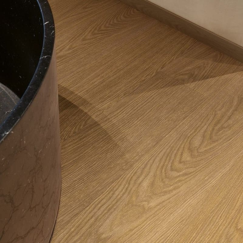 Quick-Step Cocoa Oak vinyl flooring installed in a bathroom with black bathtub showing water resistance