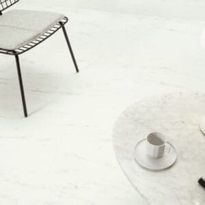 Modern living room with Quick-Step Alpha Oro Marble Carrara White vinyl flooring, featuring minimalist furniture and a round coffee table