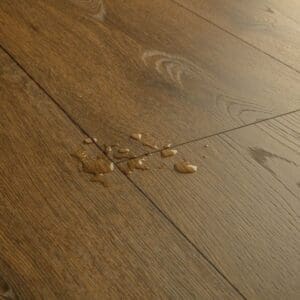 Close-up of Cocoa Brown Oak laminate showing water resistance with droplets on surface