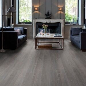 Quick-Step Alpha Blos Silk Oak Dark Grey vinyl flooring installed in an elegant living room with fireplace and grey furniture