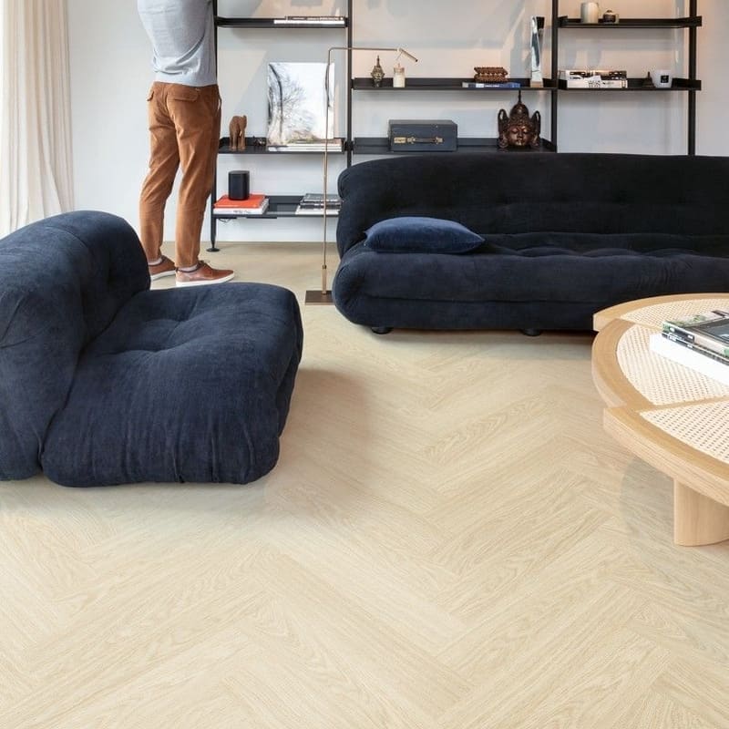 Modern living room with Quick-Step Alpha Ciro Pure Oak Polar flooring, dark blue furniture and industrial shelving