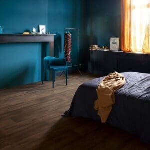 Bedroom with Quick-Step Waxed Oak Brown laminate flooring featuring teal walls and pendant lighting