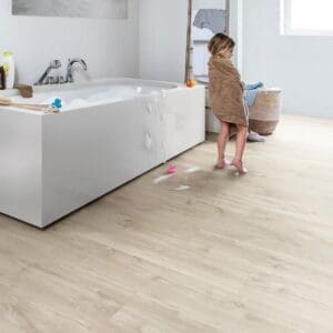 Quick-Step Canyon Oak Beige flooring installed in a bathroom with white bathtub