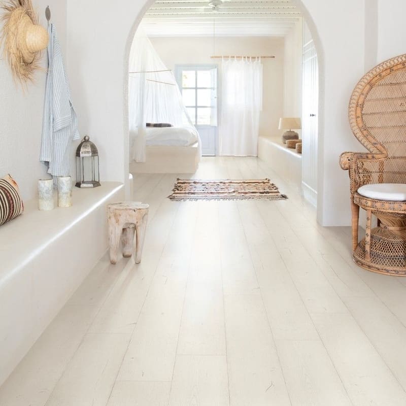 Bright white living room with white laminate flooring, white sofa and large windows