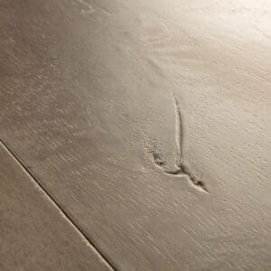 Close-up of Quick-Step Patina Oak Brown laminate showing natural wood knots and grain patterns