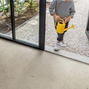 Child with yellow watering can on Oyster Concrete flooring next to indoor garden