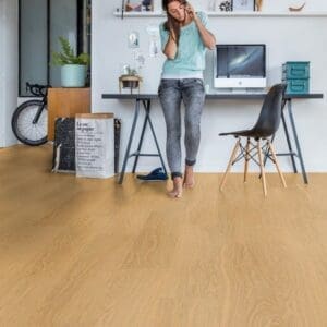 Quick-Step Alpha Bloom Pure Oak Honey vinyl flooring installed in a modern home office with desk and chair