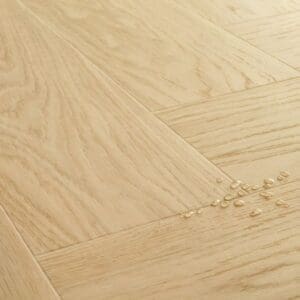 Full room view of Quick-Step Alpha Ciro Pure Oak Blush flooring installed in herringbone pattern in a modern living room