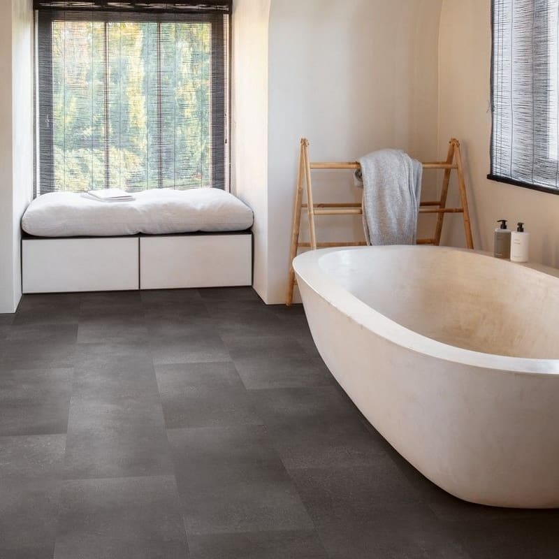 Modern bathroom with Quick-Step Alpha Oro Volcanic Rock flooring installed, featuring freestanding bath and window seat