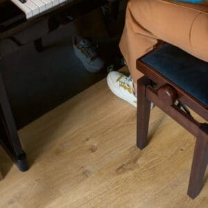 Close-up of piano keys and person playing with Cotton Oak Natural flooring visible