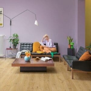 Quick-Step Alpha Blos Cottage Oak Natural flooring installed in a modern living room with purple walls and contemporary furniture