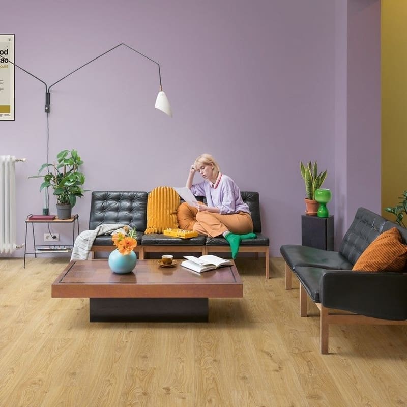 Quick-Step Alpha Blos Cottage Oak Natural flooring installed in a modern living room with purple walls and contemporary furniture