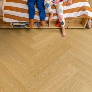 Quick-Step Alpha Ciro Pure Oak Honey vinyl flooring installed in bedroom with children sitting on bed