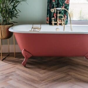 Old Bramble herringbone flooring in a bathroom with a red roll top bath