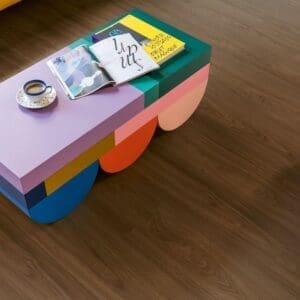 Detail view of Quick-Step Capture Chic Walnut laminate flooring with colorful coffee table