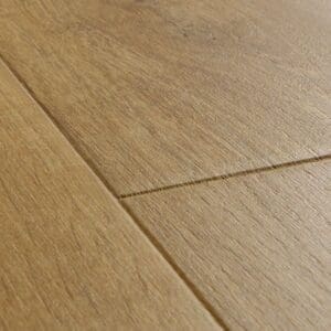 Quick-Step Impressive Soft Oak Natural laminate flooring installed in a blue bathroom with clawfoot bathtub and pedestal sink
