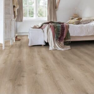 Bedroom with Quick-Step Majestic Desert Oak Brushed Grey laminate flooring installed, showing the flooring in a real-world setting